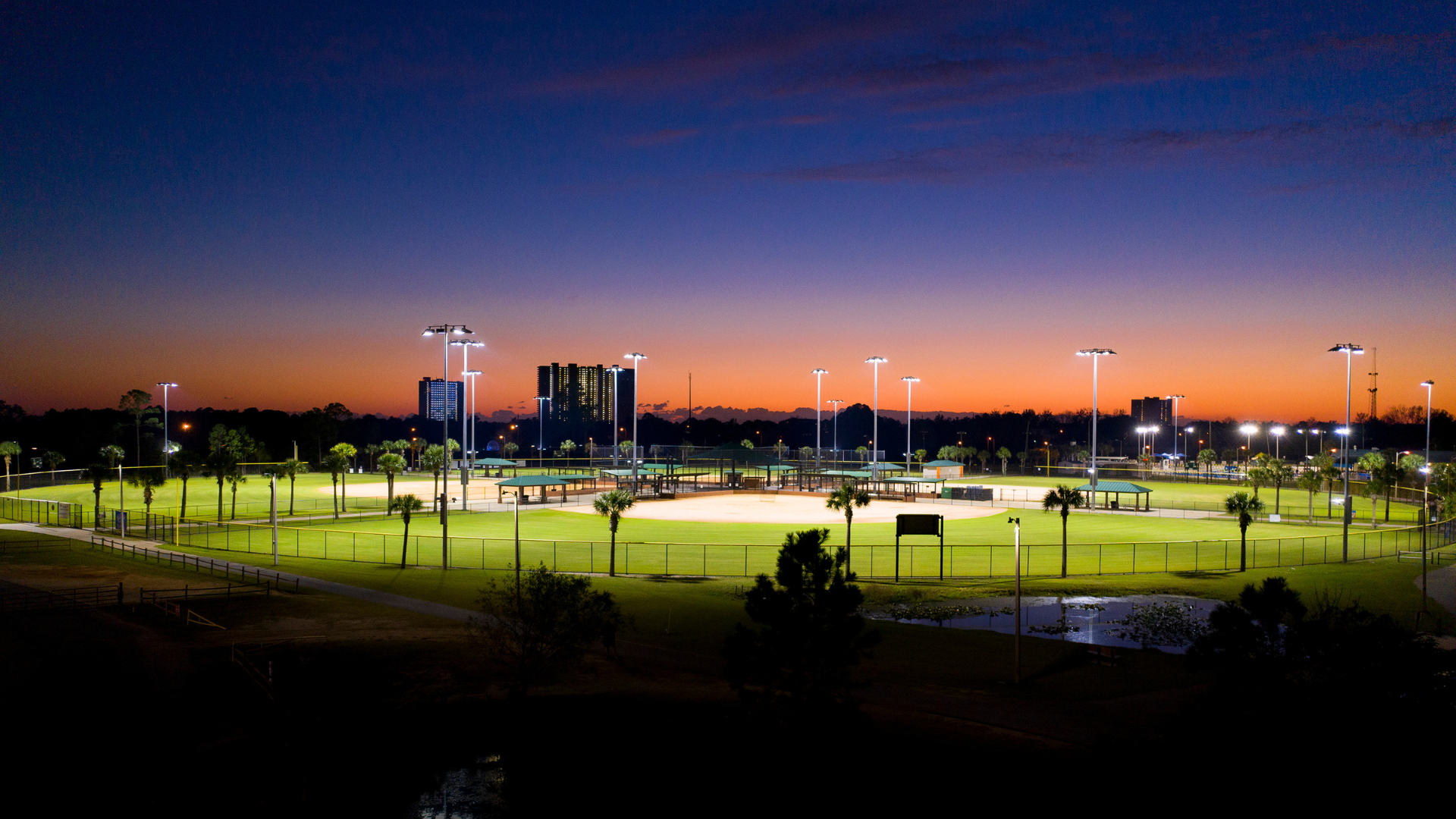 Sunset over sports field illuminated by dark sky friendly stadium lights.